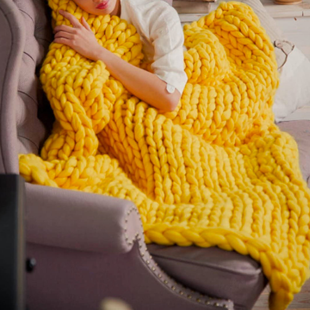 Frau mit gelber, grob gestrickter Decke auf Sofa, gemütlich, Wohnzimmer, Heimtextilien.