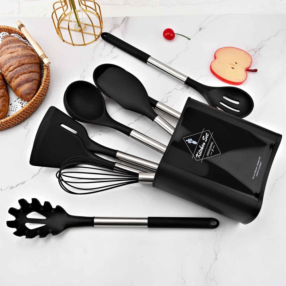 Schwarzes Küchenutensilien-Set aus Silikon und Edelstahl auf Marmorhintergrund.