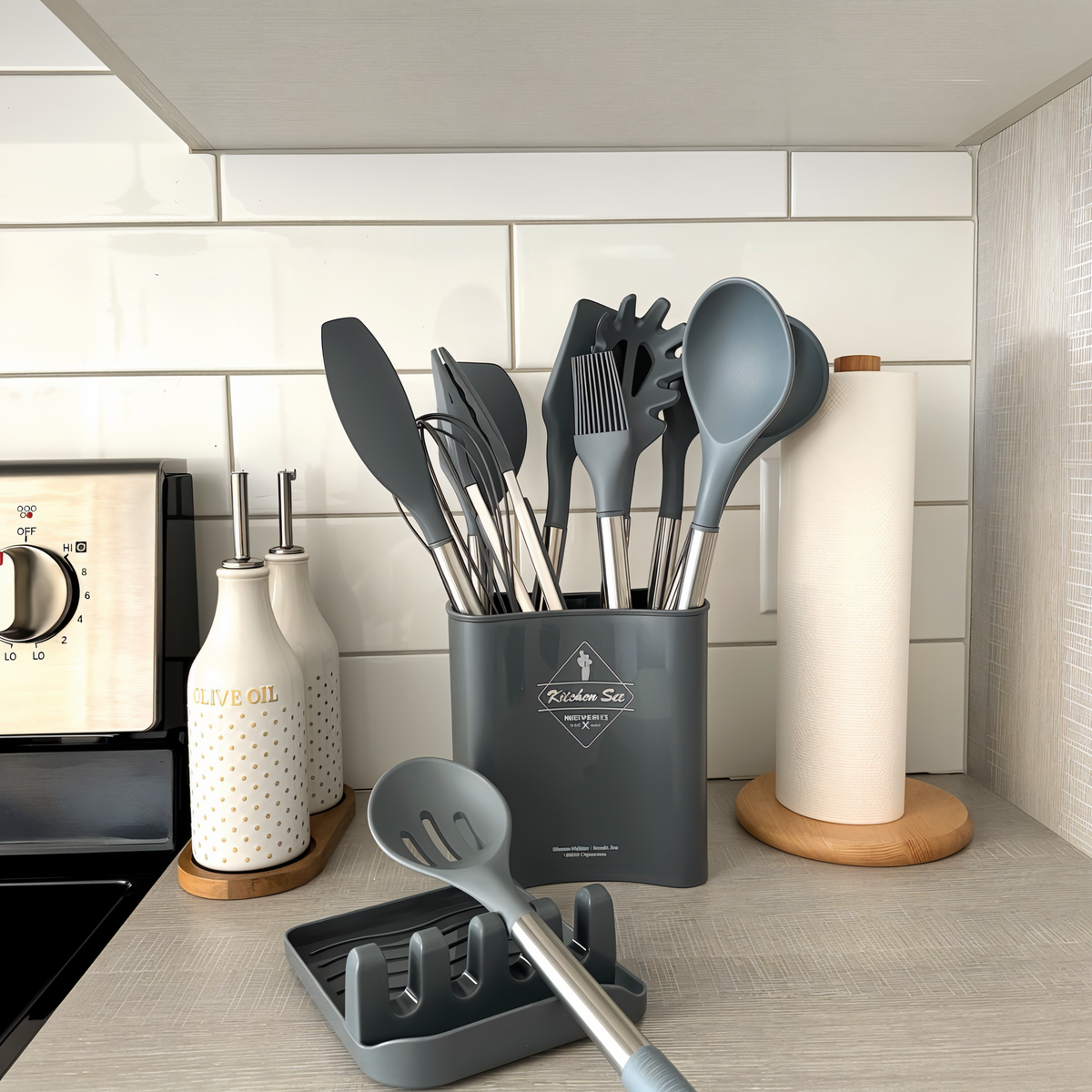 Graues Küchenutensilien-Set aus Silikon im Halter, modern, neben Öldispenser und Küchenrolle.