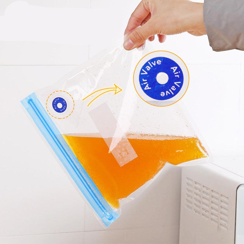 Hand hält transparenten Vakuumbeutel mit blauer Luftventil, gefüllt mit orangefarbener Flüssigkeit.