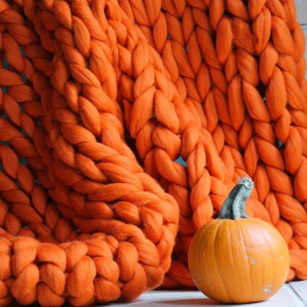 Orange gestrickte Decke aus dicker Wolle mit Kürbis, Herbstdekoration, gemütlich, warm.